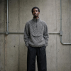 African-American man wearing a peppered grey and white boucle sweater, paired with black track pants.