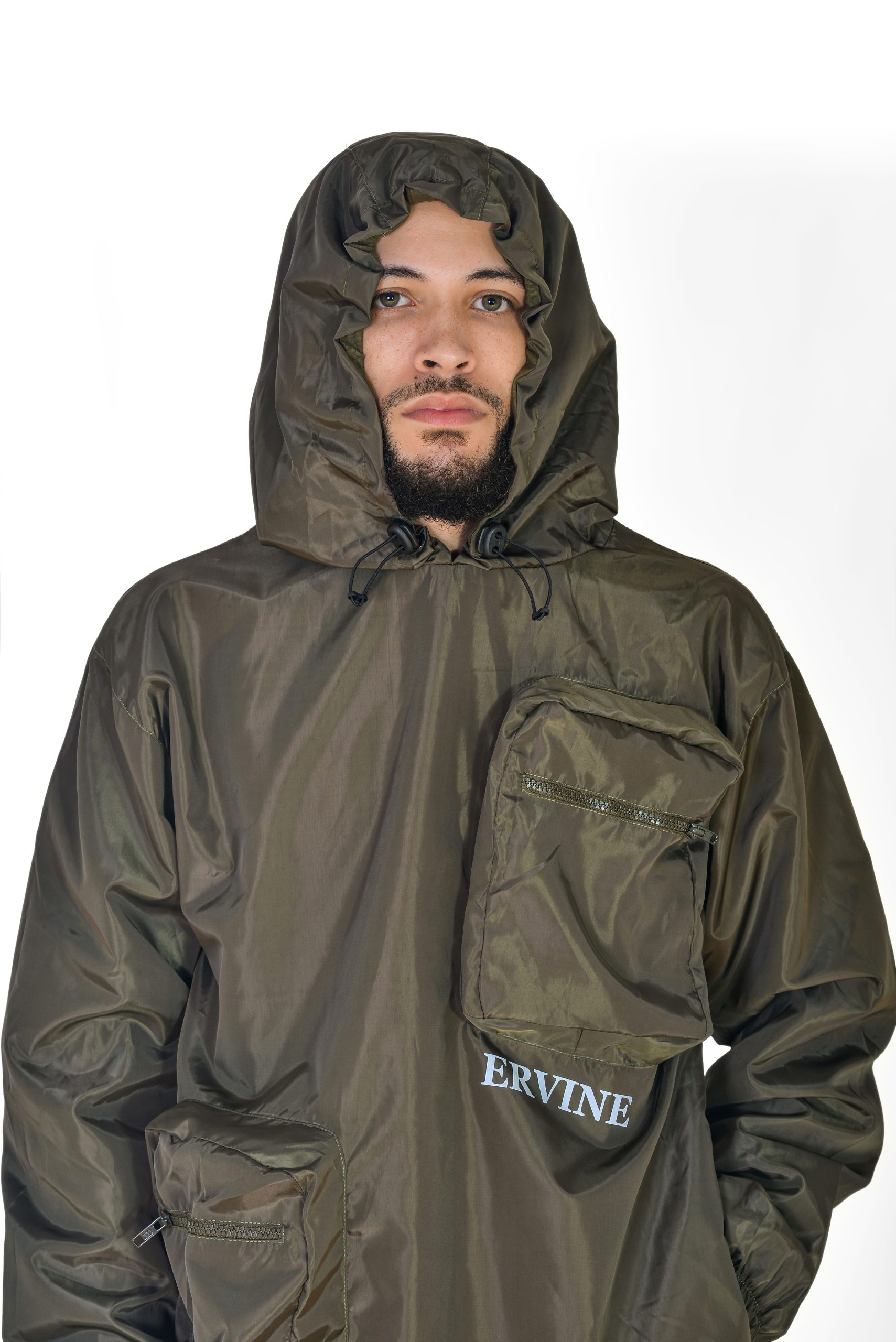 Man ERVINE wearing olive green windbreaker pullover jacket with a reflective logo and cargo pockets